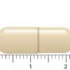 Een beige, capsulevormige Vitakruid - Gebufferde Vitamine C® (90 veganistische capsules) pil is afgebeeld naast een liniaal van ongeveer 2 centimeter lang.