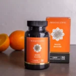 Een flesje en doosje MindScopic - MOODMASTER™ capsules (50 stuks) staan afgebeeld op een grijs vlak met twee sinaasappels op de achtergrond.