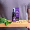 Een persoon houdt een houten plank vast met verse munt, kamillebloemen en een MindScopic - SLEEPWELL SPRAY met melatonine (15ml) flesje en doosje.