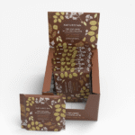 Een doos met daarin verschillende zakjes Naturecan-melkchocolade met CBD, waarvan één zakje vooraan is uitgestald. De verpakking is bruin met afbeeldingen van groene bladeren.